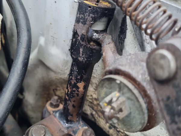 Übersicht des Motorraums einer Lancia Fulvia Berlina mit sichtbarer Schaltgestänge-Umlenkung an der Spritzwand neben Bremsanlage und Batterie.