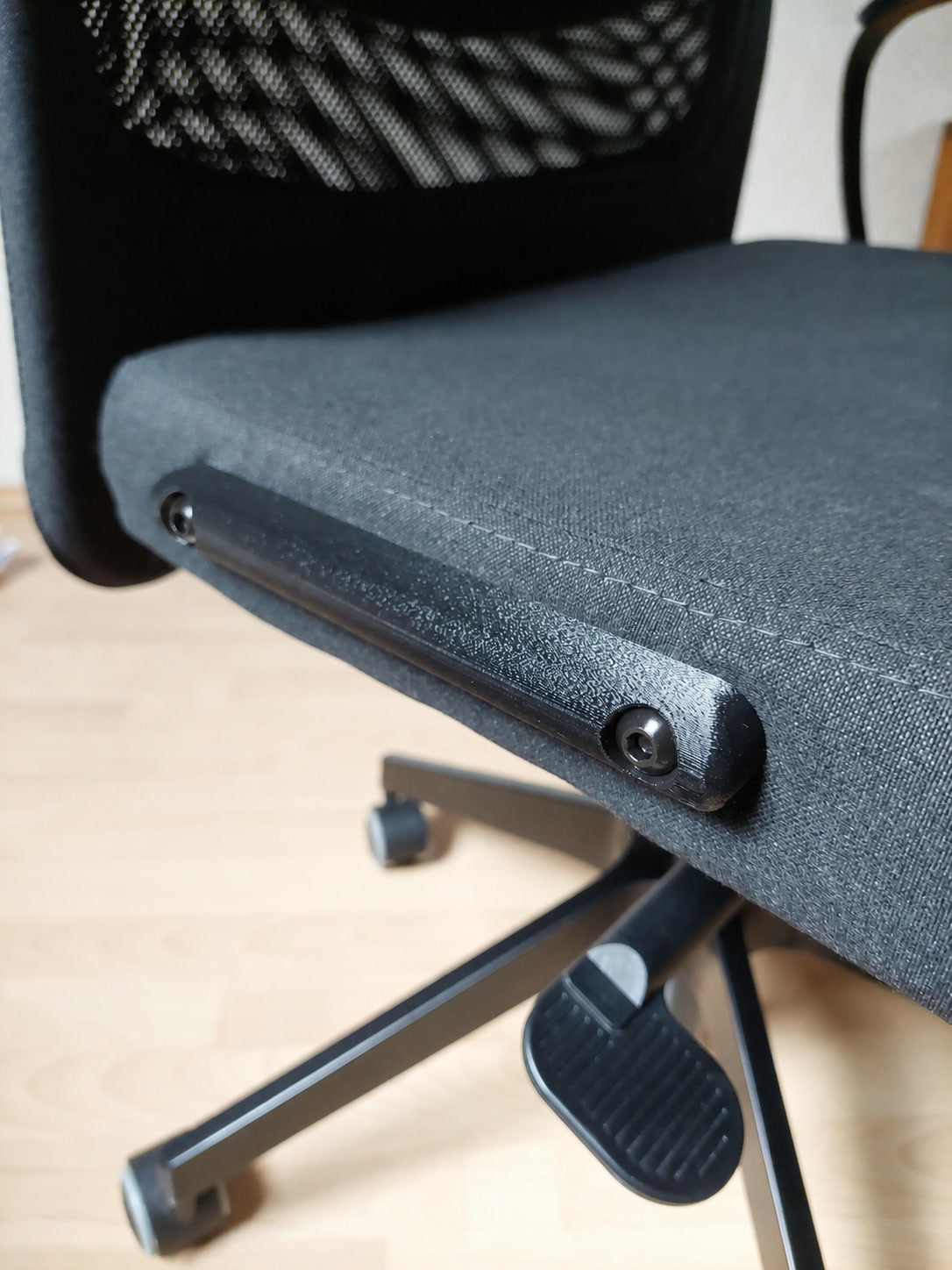 Nahaufnahme der schwarzen Armlehnen-Abdeckung mit Schrauben und Abdeckkappen am IKEA MARKUS Bürostuhl