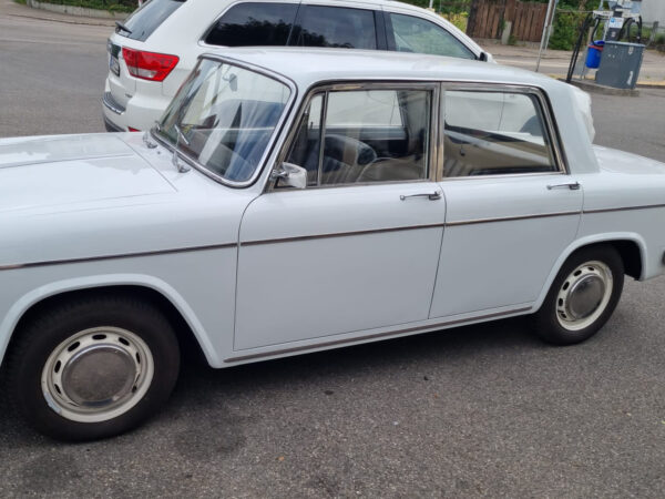Seitenansicht einer hellen Lancia Fulvia Berlina als Fahrzeugreferenz für die Lagerbuchsen der Lenkradschaltung.